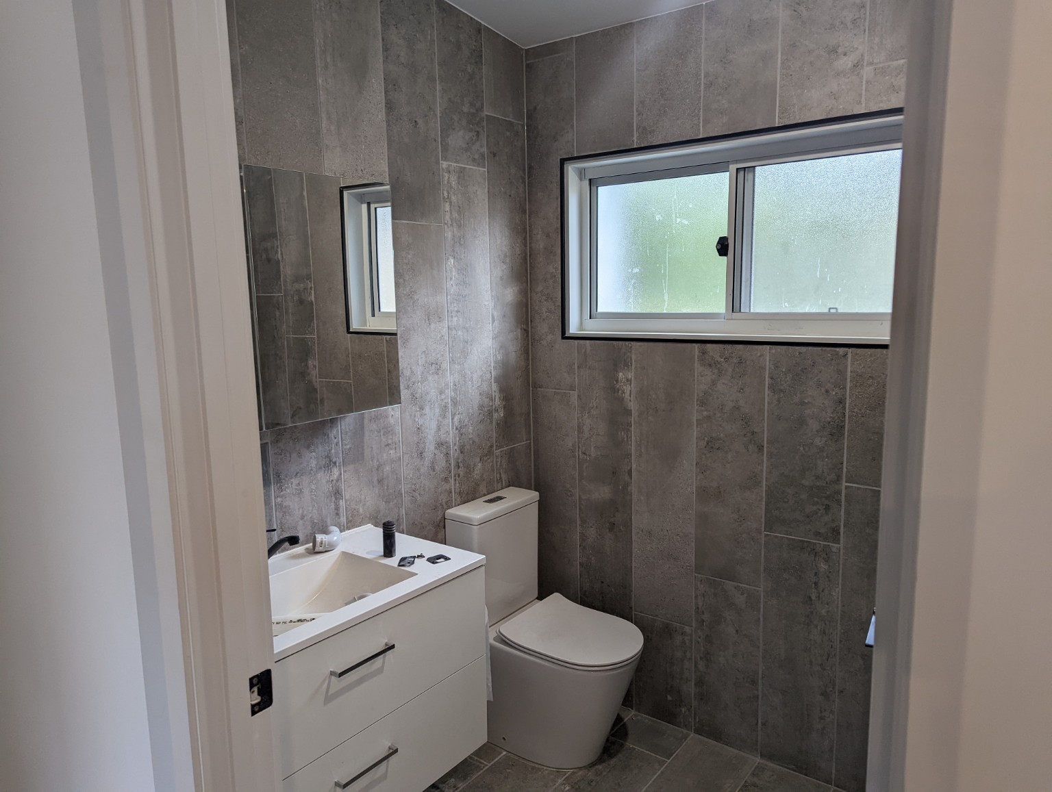 East Gosford granny flat — Bathroom with grey tiles and white vanity