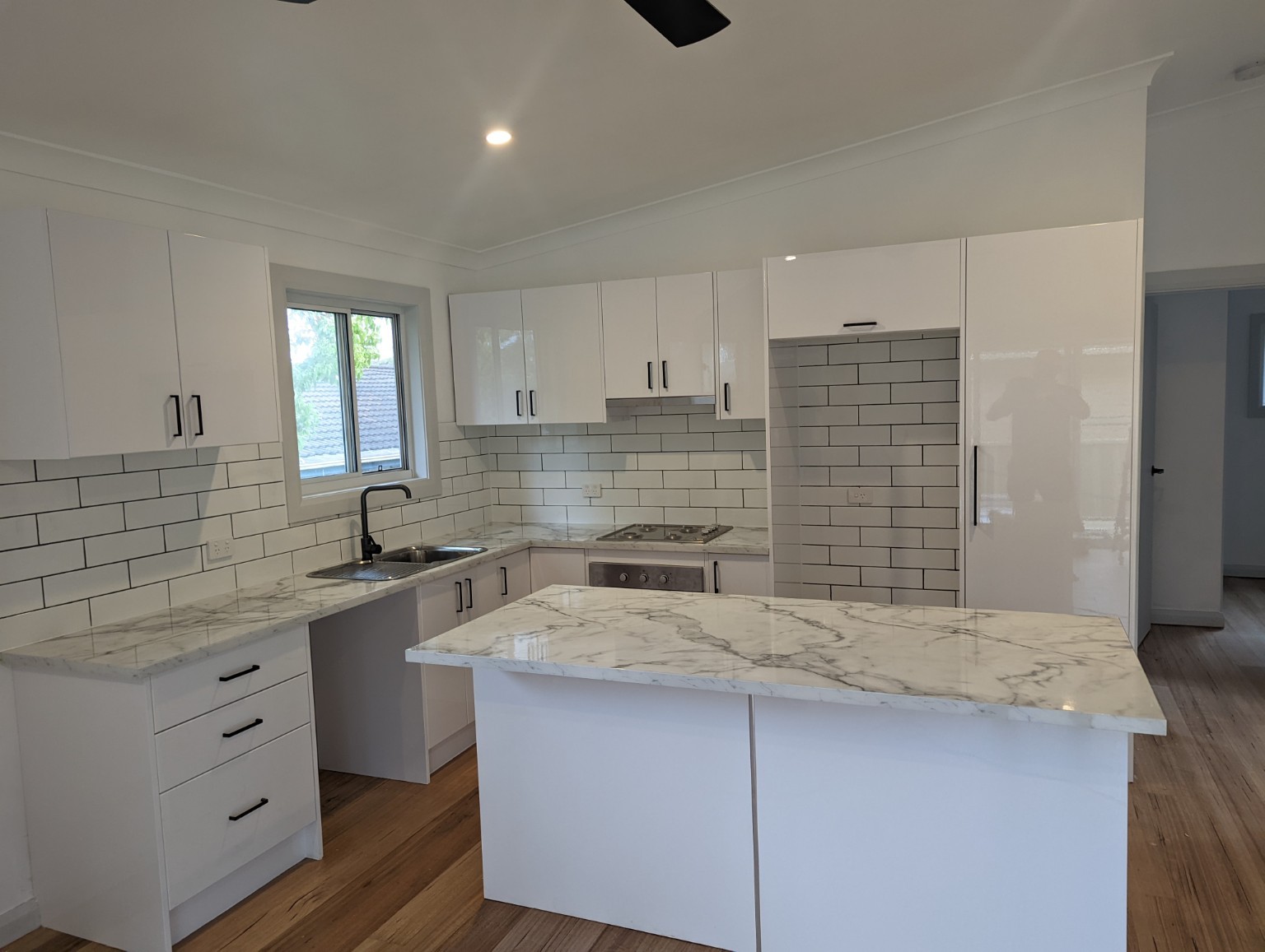 East Gosford granny flat — White kitchen with island bench and subway tile splashback