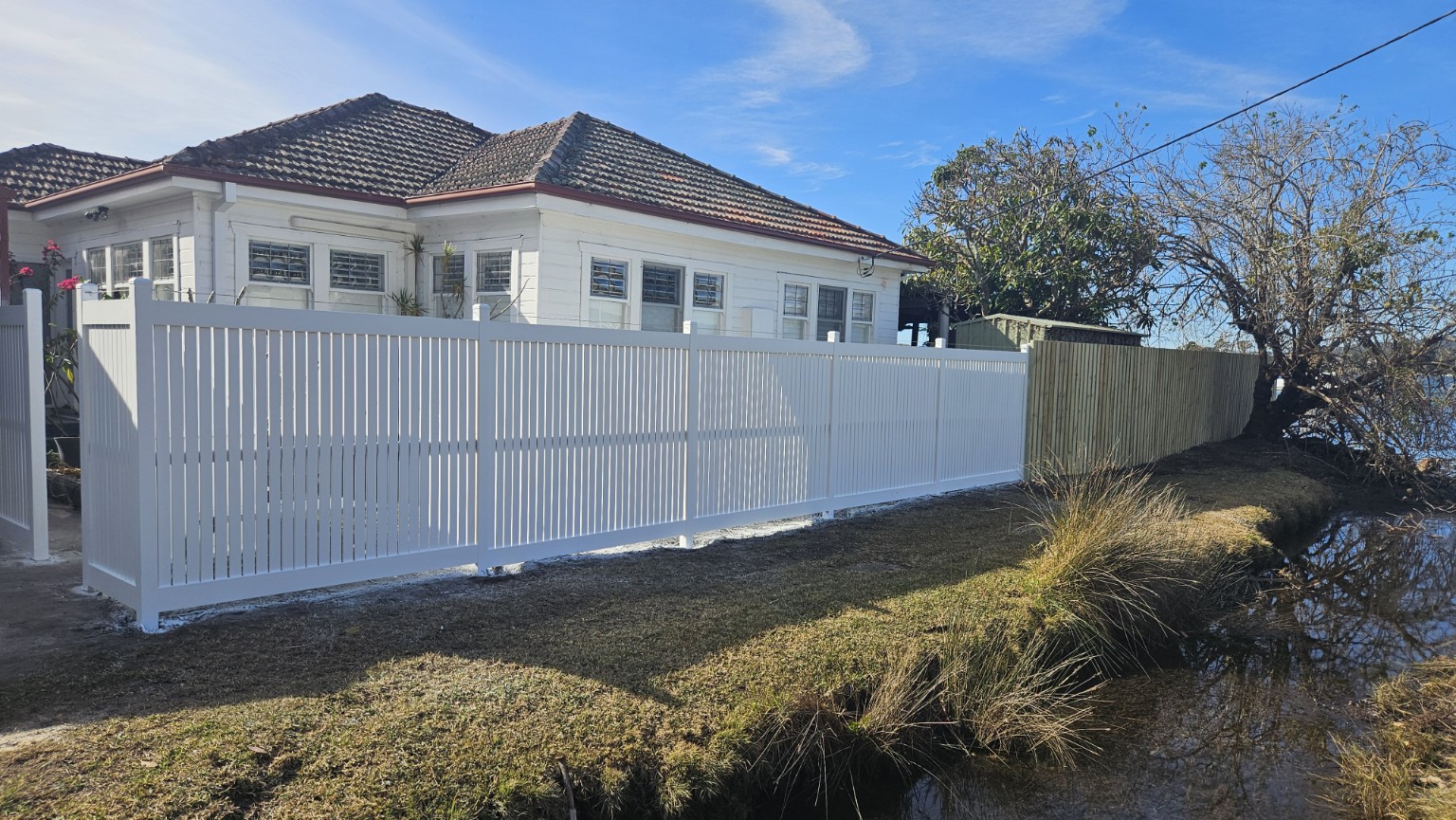 Finished white custom fence beside the waterfront at Point Clare — photograph 6