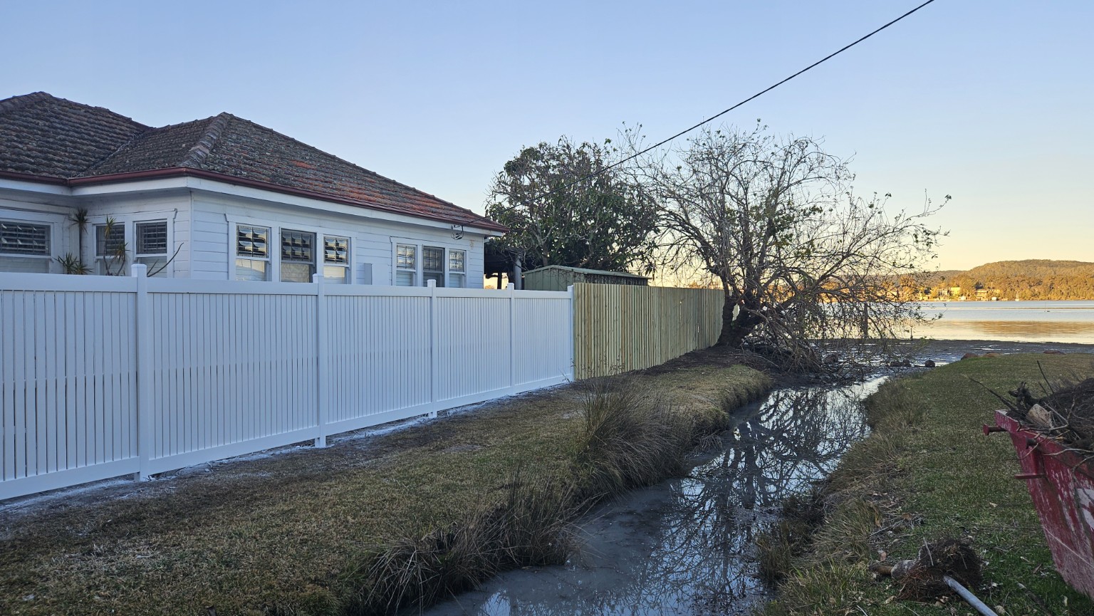 Finished white custom fence beside the waterfront at Point Clare — photograph 7
