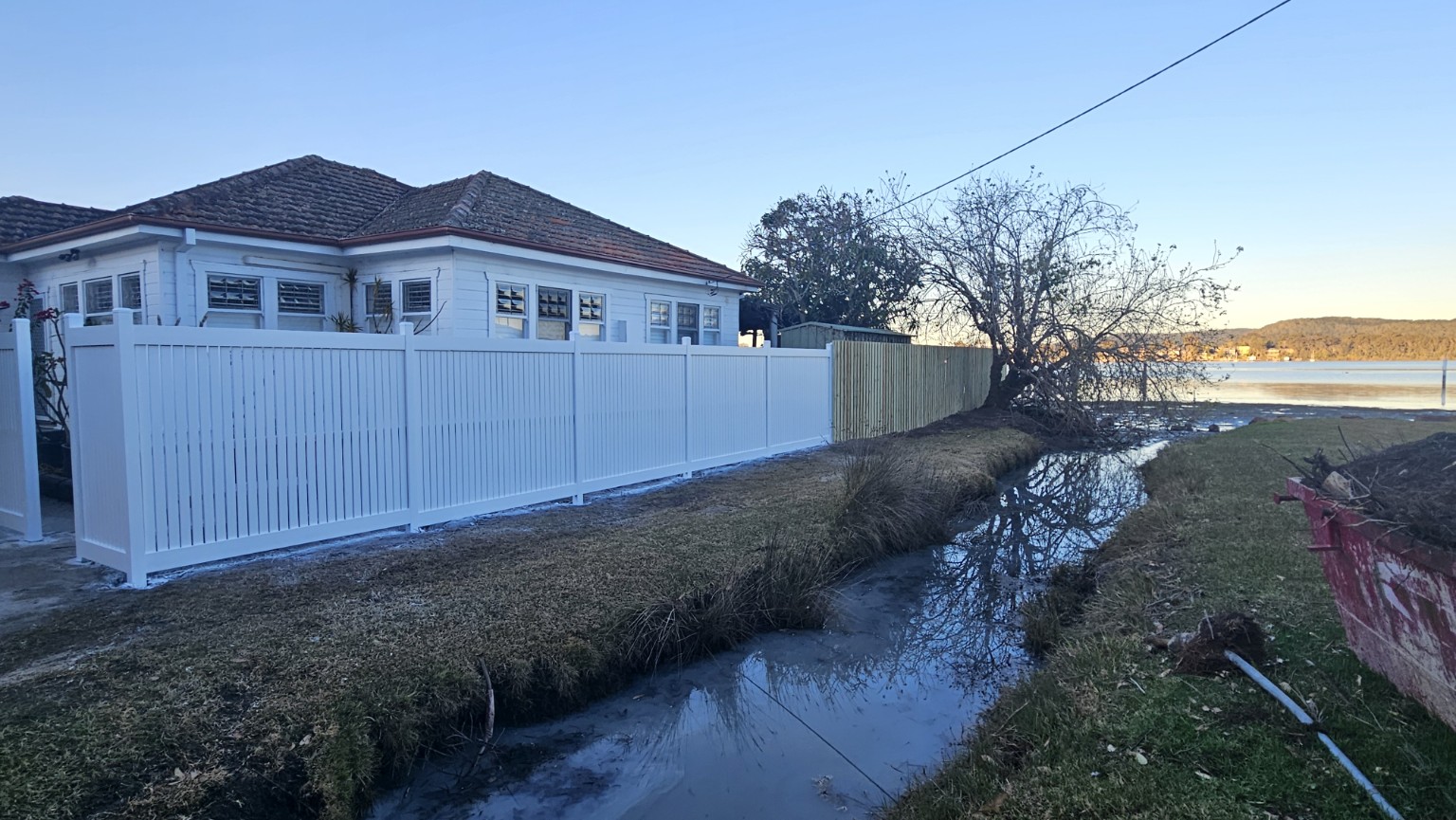 Finished white custom fence beside the waterfront at Point Clare — photograph 8